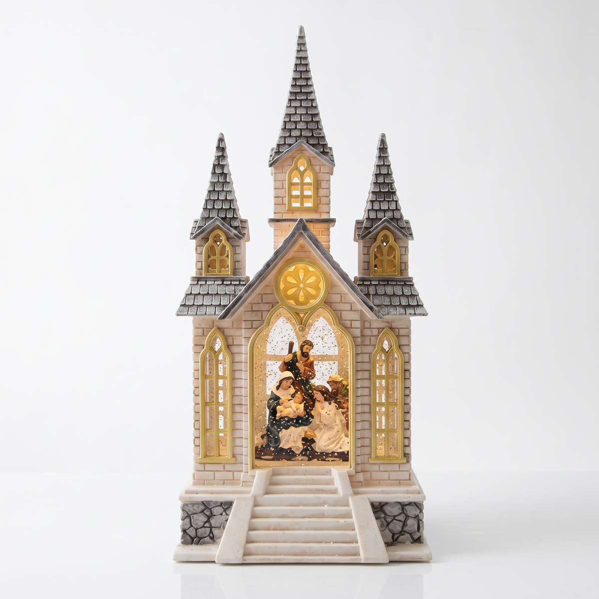 Iglesia navideña iluminada con torres y figuras en su interior